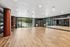 Spacious and modern exercise studio with sleek wooden flooring, large mirrors, and floor-to-ceiling windows offering lush garden views.