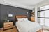 Stylish bedroom with elegant wood furnishings, a cozy bed, and abundant natural light from a large window.