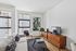 Modern living room with cozy gray sofa, sleek TV stand, abstract artwork, and large windows offering natural light.