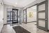 Modern apartment lobby with sleek glass doors, stylish lighting, and contemporary artwork, creating a welcoming entrance.