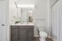 Bright, modern bathroom with sleek gray vanity, elegant fixtures, and chic decor.