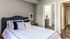 Elegant bedroom with cozy bedding, plush pillows, and en-suite bathroom in a modern apartment.
