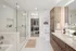 Elegant bathroom featuring a modern glass shower, sleek vanity with wood finish, and a spacious walk-in closet.