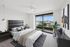 Luxurious bedroom with modern decor and expansive city view from floor-to-ceiling windows, featuring elegant furniture and artistic elements.
