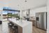 Sleek modern kitchen with spacious island, elegant lighting, and an open view to a sunny patio.