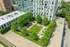 Aerial view of a modern apartment building with a lush, green rooftop garden featuring a spacious lawn, seating areas, and a pergola for outdoor relaxation.