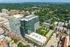 Aerial view of modern high-rise apartments surrounded by lush greenery and vibrant cityscape, offering urban living with scenic views.