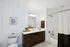 Elegant bathroom with modern vanity, large mirror, and inviting bathtub, perfect for relaxation.