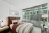 Bright and modern bedroom with a cozy bed, large windows, and contemporary decor enhancing a city view ambiance.