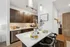Modern kitchen with sleek dark wood cabinets, quartz countertops, and stylish pendant lighting in a bright, inviting apartment.