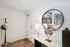 Chic apartment entrance with stylish decor featuring a sleek mirror, modern lamp, and elegant hat stand, leading into a contemporary kitchen.