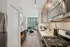 Contemporary urban apartment kitchen with sleek stainless steel appliances, modern cabinetry, and a cozy open living area with large windows for natural light.
