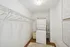 Modern laundry room with stacked washer and dryer, ample hanging space, and minimalist decor.