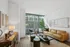 Modern living room with expansive windows, stylish tan sofa, chic coffee table, and vibrant green plant, harmonizing natural light with elegant design.