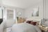 Bright and modern bedroom featuring a cozy bed with stylish pillows, elegant artwork, and natural light filtering through large windows.