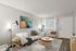 Modern living room with a cozy white sofa, stylish artwork, wooden coffee table, and natural light through large window.