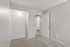Cozy room with soft carpet flooring and warm lighting, leading to a bright kitchen area.