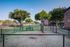 Charming apartment complex with well-maintained green spaces, mature trees, and a cozy fenced seating area, perfect for relaxation.