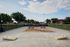Inviting outdoor communal area featuring picnic tables and a cornhole game set amidst lush greenery and clear skies.