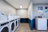 Modern and efficient laundry room with a row of sleek white washers, dryer, and a folding table, perfect for convenient apartment living.