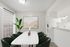 Elegant dining area featuring a marble-top table, lush green chairs, and modern art, bathed in natural light.