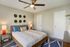 Inviting modern bedroom featuring a cozy bed with vibrant cushions, contemporary wall decor, and stylish bedside lamps.