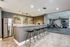 Chic apartment interior with modern bar area, stylish stools, and an adjacent gym space.