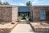 Charming brick exterior of a modern apartment with a welcoming entrance accented by lush potted plants and a sleek double door.