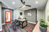 Modern office space with a vibrant orange door, sleek black chairs, stylish desk, and contemporary wall art, featuring elegant green plants for a refreshing touch.