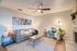 Chic living room featuring stylish artwork, cozy gray sofa, vibrant blue armchair, and modern decor under a sleek ceiling fan.