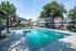 Inviting swimming pool area in a charming apartment community, featuring lush greenery, elegant lounge chairs, and shaded seating areas.