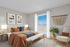 Inviting bedroom with a chic design featuring a cozy bed with warm-toned bedding, elegant wall art, and abundant natural light from a large window.