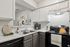 Bright and modern kitchen with sleek countertops, stylish cabinetry, and a cozy coffee corner.
