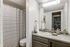Modern bathroom with elegant fixtures, sleek vanity, and stylish striped shower curtain, offering a tranquil and sophisticated ambiance.
