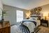 Cozy bedroom with modern decor, featuring elegant wicker wall art, plush carpeting, and ambient lighting for a warm atmosphere.