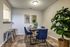 Chic dining nook with elegant blue chairs, a contemporary table, lush greenery, and stylish wall mirrors.