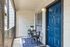 Inviting apartment entryway with a stylish blue door, cozy seating area, and decorative plant, exuding charm and warmth.