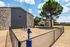 Charming brick apartment building with fenced yard, vibrant greenery, and a serene atmosphere under a sunny sky.