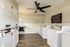 Modern laundry room with sleek white washers and dryers, laminate wood flooring, and a ceiling fan for comfort.