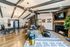 Chic open-concept living space with vaulted ceilings and modern lighting, featuring a cozy seating area, stylish office nook, and a sleek fireplace.