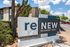 Modern apartment complex entrance with stylish 'ReNew Fairmont Park' signage surrounded by lush greenery and a bright, welcoming exterior.