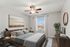Inviting bedroom with modern decor, featuring a large window, stylish ceiling fan, and cozy bedding.