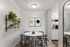 Chic dining area with a round marble table, modern black chairs, and stylish wall art, adjacent to a bright kitchen.