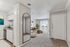 Welcoming apartment entryway leading to a modern kitchen and cozy living room with large windows and abundant natural light.