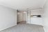 Bright and airy living space with neutral tones, plush carpeting, and convenient open shelving leading to a cozy kitchen nook.