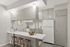 Chic modern kitchen with minimalistic design, featuring a breakfast bar, wooden stools, and sleek white cabinetry.