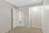 Cozy apartment interior with soft carpet flooring, modern white door, and bright lighting leading to a functional kitchen space.