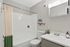 Elegant bathroom with a minimalist design, featuring a chic shower curtain, decorative plants, and a bright ambiance.