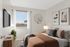Cozy bedroom with warm earthy tones, featuring a plush bed, decorative modern art, and a large window inviting natural light.