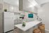 Chic modern kitchen with sleek white cabinetry, elegant countertops, and stylish wooden stools, accented by vibrant artwork and a fresh bouquet of white flowers.